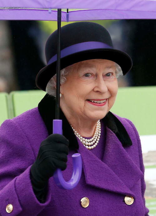 The queen wearing Alfreds hat and matching purple outfit